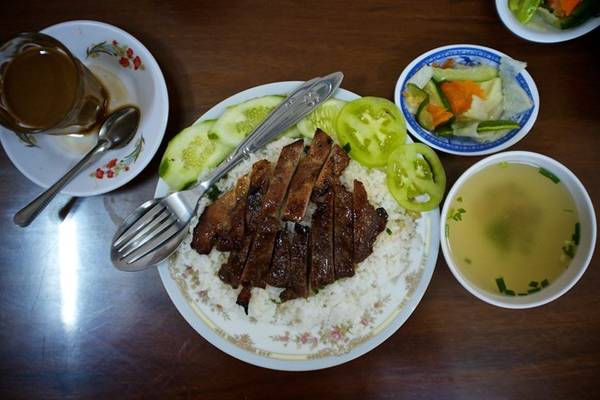 Bai sach chrouk (Cơm thịt heo): Đây là món ăn rất đơn giản nhưng ngon tuyệt, phổ biến khắp xứ chùa tháp. Thịt lợn thái mỏng, nướng từ từ trên than đá để giữ được vị ngọt tự nhiên. Đôi khi thịt lợn có thể được ướp nước cốt dừa và tỏi. Thịt được bày trên cơm tấm, với dưa góp và gừng. Bạn sẽ có thêm một bát nước dùng gà để ăn cùng. Ảnh: Nyampenh.