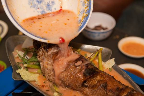 Cá om: Cá được rán nguyên con, sau đó cho lên nồi lẩu cùng cà ri cốt dừa cay ngọt, thêm các loại rau như bắp cải, ăn kèm mì gạo. Ảnh: Blind-eye-productions.