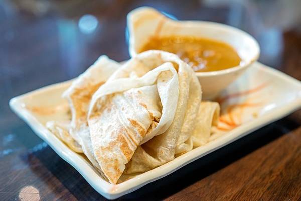 <strong>Roti canai:</strong> Đây là món ăn sáng điển hình của Malaysia, có nguồn gốc từ Ấn Độ. Tuy nhiên, bạn có thể thưởng thức vào bất cứ thời điểm nào trong ngày. Bột mì, trứng và ghee (bơ đun chảy và bỏ bớt nước) được trộn đều, tán mỏng trên chảo nướng và sau đó gập lại. Món này rất ngon khi ăn nóng, với ruột mềm và vỏ giòn. Roti canai thường được dùng kèm cà ri. Ảnh: Michael Shum/Flickr.