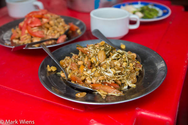 Các lá trà muối chua chua, đắng được trộn với bắp cải thái sợi, cà chua, đậu rán giòn