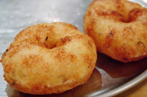 Vada Những chiếc vada có hình giống bánh vòng doughnut cũng dễ gặp vào các bữa ăn sáng. Tuy nhiên, vada không được bọc bằng đường, chúng hợp với người thích ăn đồ cay, nóng, và giòn. Vada làm từ bột nhão với đậu lăng đen, chút hạt tiêu, bột cà ri, thìa là, ớt và hành. Bánh vada ngon nhất khi bạn ăn cùng với tương ớt xoài, dừa.