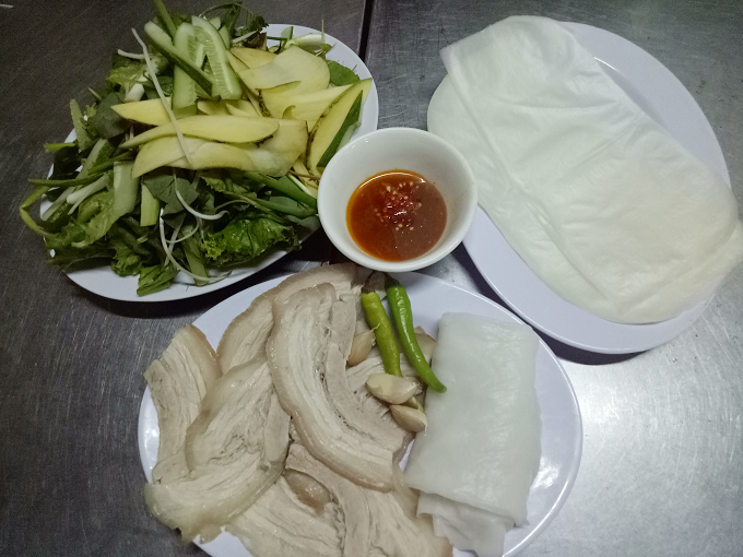 Bánh tráng cuốn thịt heo Khâu chọn lọc nguyên liệu cho món này khá cầu kỳ. Bánh tráng phải là loại phơi sương, thơm mùi gạo. Thịt heo chọn loại ngon, luộc vừa tới rồi ngâm trong nồi nước dùng, sao cho miếng thịt có độ dẻo, phần mỡ trong, phần thịt trắng nõn nà, bì mềm. Trong chợ có tiệm bánh tráng thịt heo của cô Hà (số lô 12 Đình 15A). Suất ăn dành cho một người là 30.000 đồng và 2 người là 50.000 đồng.