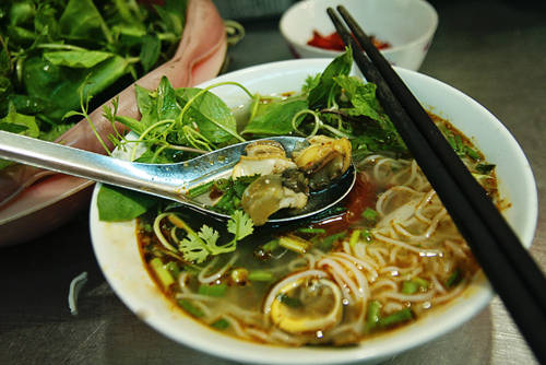 Bún riêu ốc: Món này ngon nhất là phần nước dùng, nước ăn vừa miệng, thơm nhẹ vị nếp cái dùng làm giấm bỗng, thêm chút cay cay của ớt. Ngoài nước dùng ngon, ốc được xử lý kỹ nên không có vị tanh mà thịt rất mềm, chắc, ăn giòn giòn, béo ngậy. Quán bún ốc trong ngõ chợ Đồng Xuân là địa điểm bạn nên ghé thử. Bún ốc thường được ăn kèm với rau sống. Vị béo ngậy của từng con ốc cùng nước dùng thanh chua sẽ để lại nhiều ấn tượng trong hành trình khám phá ẩm thực đất Hà thành của bạn. Ảnh: Phong Vinh.