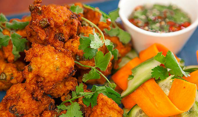 Chả cá kiểu Thái được rán ngay tại quầy, trong một chiếc chảo lớn luôn xèo xèo mỡ, mùi thơm nghi ngút chắc chắn sẽ thu hút khách qua đường. Từng miếng chả cá dai, thịt cá ngọt quyện lẫn với vị thơm của lá chanh, mùi tàu và đậu, được chấm kèm với tương ớt chua ngọt, cay cay rất thú vị.