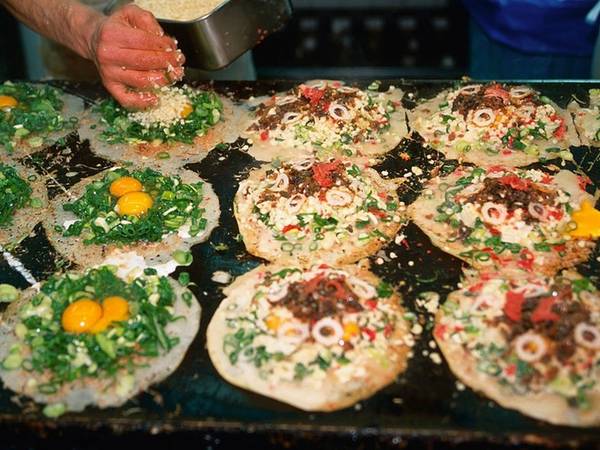 Okonomiyaki là món bánh xèo mặn, đặc sản của vùng Osaka và Hiroshima. Bên trên bánh được cho thêm nhiều thành phần khác nhau tùy theo vùng miền nhưng luôn có nước dùng dashi, trứng, cải xắt mỏng và thịt.