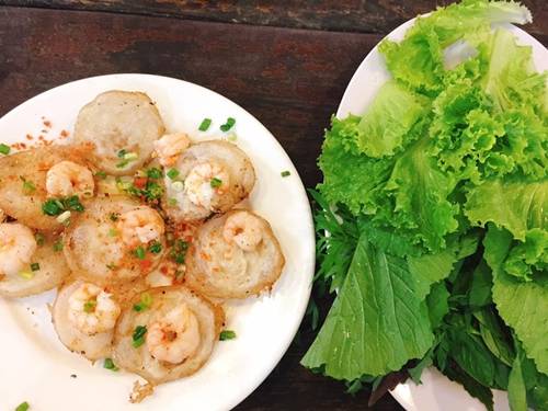 Bánh khọt Món ăn dân dã được đông người ghé ăn và mua về. Bột bánh khọt đổ trên những chiếc khuôn nhỏ, cho thêm một con tôm. Khi chín, gắp ra đĩa, ăn cuốn rau cải, rau xà lách, bánh tráng… Quán bánh khọt nổi tiếng nhất là Cô Ba, giờ là nhà hàng, không gian sang trọng. Một số quán khác là Bà Hai, Út Loan, Gốc Vú Sữa… Giá một phần từ 40.000 đồng. Ảnh: Kiều Trinh.
