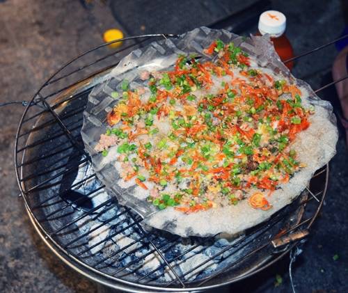 Bánh tráng nướng Còn được gọi là "pizza Đà Lạt", bánh tráng nướng gồm lớp nhân trứng, phô mai, bò khô trên tấm bánh tráng nướng giòn.Bạn có thể ghé ngã tư Mạc Đĩnh Chi giao với Huỳnh Thúc Kháng, đường 19/5, đường Trần Bình Trọng… để thưởng thức món này với giá 10.000 đồng một cái. Ảnh: Má Lúm.