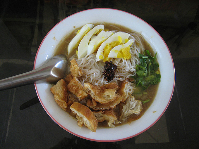 Bún cá Mohinga gồm một quả trứng luộc thái lát và akyaw (rau chiên giòn) cùng một đĩa bột đậu lăng. Ảnh: Saveur.