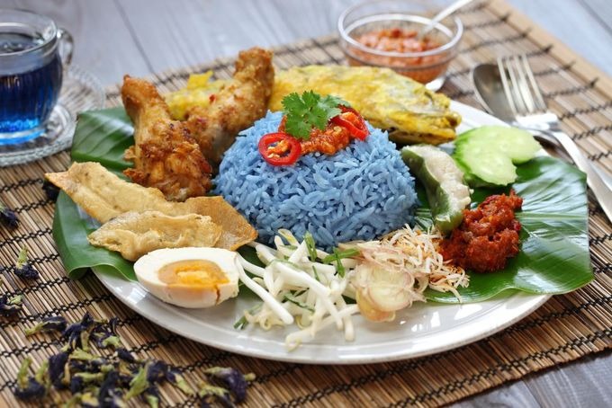 Nasi kerabu  Cơm được nấu từ gạo màu xanh hay còn gọi là gạo thảo mộc. Sau khi nấu chín, cơm thường được ăn kèm cùng trứng muối, nước sốt, cá hồi chiên giòn, gà rán.  Một suất thường được bán với giá khoảng 9 RM (50.000 đồng). Bạn có thể thưởng thức nasi kerabu ở nhà hàng Nasi kerabu Keramat hay Nasi kerabu Kambing Barkar ở thủ đô Malaysia. Ảnh: Shutterstock/Bonchan.