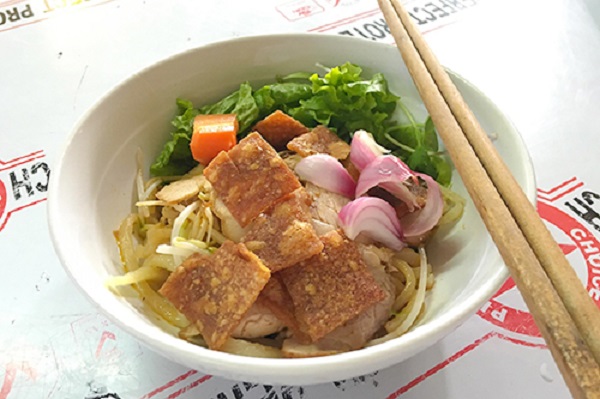 Cao lầu  Cao lầu là món ngon mà bất kỳ du khách nào tới Hội An cũng nên thử một lần. Từng được báo Anh khen ngợi là món ăn "chứa đựng lịch sử của cả Hội An", một tô cao lầu ngon phải có sợi mì vàng mềm mại được làm từ nước giếng cổ, nhào kỹ.  Những sợi mì được đặt gọn ghẽ dưới đáy tô cùng một ít giá trụng, rau quế, húng lìu, bên trên là vài lát thịt xá xíu, tôm, thịt gà, da heo chiên giòn. Thực khách cho thêm ớt xanh ăn kèm sẽ ngon hơn. Mỗi tô có giá từ 30.000 đồng. Ảnh: Di Vỹ.
