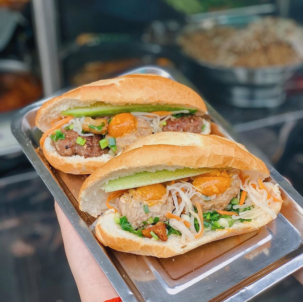 Các công đoạn để chế biến món ăn này khá đơn giản. Đầu tiên, người bán sẽ phết một lớp mỡ hành mỏng vào ruột bánh, tiếp đến là một ít đồ chua. Thịt bò nướng và xíu mại trứng muối là 2 nguyên liệu được cho vào sau cùng. Nếu muốn thưởng thức với hương vị đậm đà hơn, bạn có thể rưới thêm một ít nước mắm lên phần nhân bên trong. Ảnh: Mysteriousaigon.