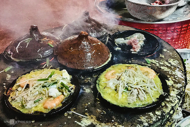 Một bếp có 6-9 khuôn nướng bánh xèo Phan Thiết bằng than củi bên dưới.