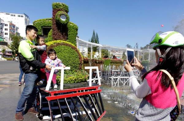 Một gia đình thích thú chụp hình bên đoàn tàu kết bằng hoa ở đài phun nước trước chợ đêm Đà Lạt sáng 28-12- Ảnh: C.THÀNH