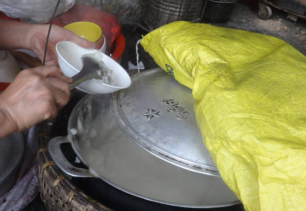 Nồi bánh đúc nghi ngút khói, được ủ ấm xung quanh bằng vải bông lèn chặt. Có khách, cô Hạnh chỉ mở hé vung nồi đang nghi ngút khói, múc bánh thật nhanh rồi đậy ngay vào cho ấm. Bánh đúc ở đây mềm, không quánh đặc như các quán khác nhưng rất dễ ăn và dễ xúc. Ảnh: Tuyết Mai.