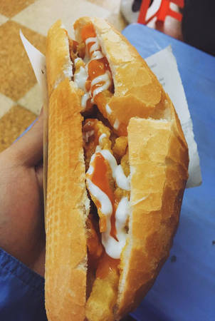 Bánh mì nướng nóng tại phố ẩm thực Hàm Long bỏ thêm nem chua, khoai tây chiên, sốt mayonnaise, tương ớt và dưa chuột. Chiếc bánh có vị giòn tan, bở mềm, béo ngậy với giá khoảng 20.000 đồng. Ảnh: Phạm Tuấn Lâm