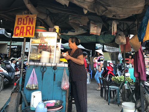 Không gian quán bún cà ri Tân Châu được che chắn bởi tấm dù bạc màu
