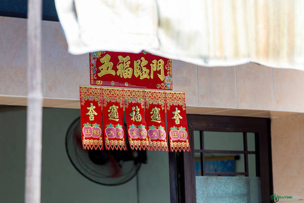 Phía trước một số gia đình có dán miếng giấy đỏ với hàng chữ Hoa màu vàng nổi bật