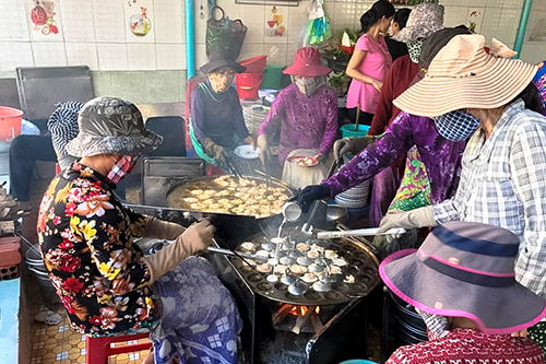 Gần chục người luôn tay đổ bánh trên chiếc lò gang lớn đun bằng củi mà vẫn không kịp phục vụ khách. Ảnh: Di Vỹ.