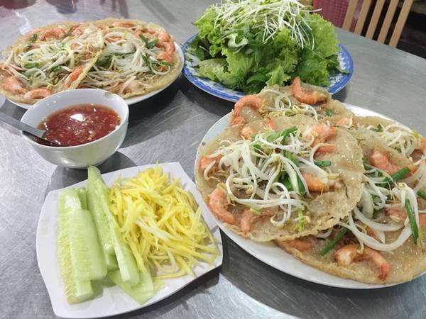 Bánh xèo tôm nhảy Bình Định Món bánh xèo nổi tiếng xứ Nẫu làm phong phú ẩm thực Đà Nẵng. Thực khách khó lòng từ chối chiếc bánh xèo được đổ trên lò than hồng, những con tôm đất tươi và giá đỗ rải lên mặt bánh. Thực khách có thể ăn bánh trực tiếp hoặc cuốn với rau xà lách, bánh tráng, chấm với mắm nêm, bỏ thêm tỏi ớt cay xé lưỡi. Ở Đà Nẵng có nhiều quán bánh xèo tôm nhảy như Năm Hiền, Cô Ba… giá 20.000 đồng một cái.