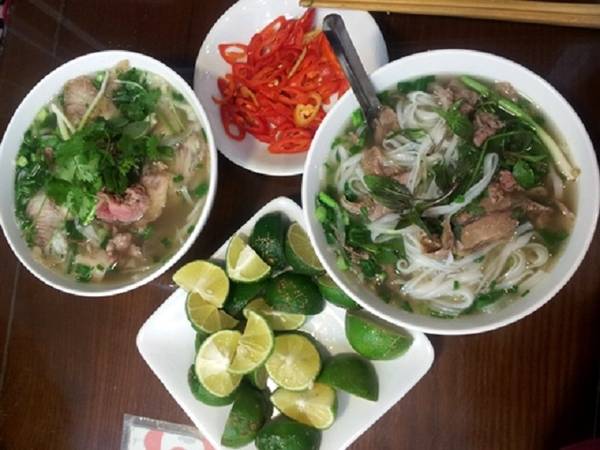 Phở Lý Quốc Sư: Một trong những thương hiệu phở nổi tiếng nhất nhì đất Hà Thành nằm trên phố Lý Quốc Sư. Phở ở đây nức tiếng từ lâu bởi thứ nước dùng đặc trưng; thơm mùi gia vị mà không bị béo. Cái khéo léo của những chủ nhân đời đầu trong công thức nấu phở, được truyền lại cho con cháu làm món ăn nổi tiếng tới ngày nay. Đặc biệt, phở Lý Quốc Sư chỉ chuyên về các món bò với đủ loại tái, chín, nạm, gầu. Tô phở đầy đặn, ăn kèm với quẩy giòn, vàng ruộm và các loại rau sống. Quán phục vụ bữa sáng 6h - 14h và tối 17h30 - đến 22h. Giá một tô phở dao động 45.000 - 75.000 đồng. Ảnh: Hương Chi.