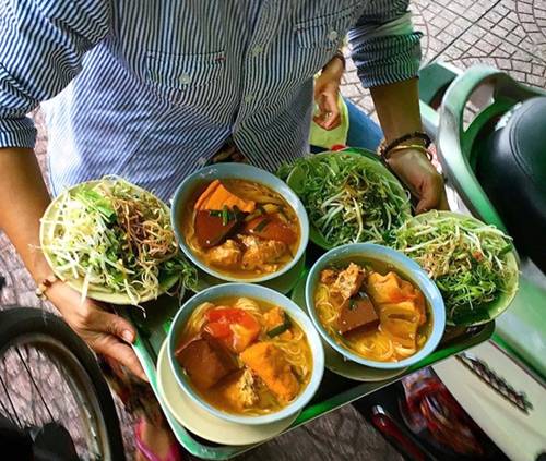 Bún riêu chợ Bến Thành  Trước đây là gánh bún riêu vỉa hè, nay đã thành quán, bán cả ngày ở đối diện cửa Đông luôn nườm nượp khách. Nhất là xế chiều, nhiều người đến đây thưởng thức tô bún có màu sắc hấp dẫn, thịt riêu chắc và thơm, cà chua thêm màu bắt mắt. Sợi bún mỏng, nước lèo đậm đà tạo hương vị đặc trưng của quán. Giá một tô là 38.000 đồng, cao so với nhiều quán bún riêu khác nhưng luôn đông khách ghé ăn. Ảnh: Hà Nguyên.