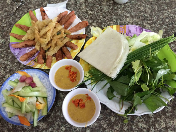 Nem cuốn với bánh tráng, rau sống, dưa chua và bánh tráng chiên giòn, chấm nước tương đậu phụng...