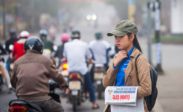 Cô bé sinh viên bán báo trong buổi sáng mờ sương.