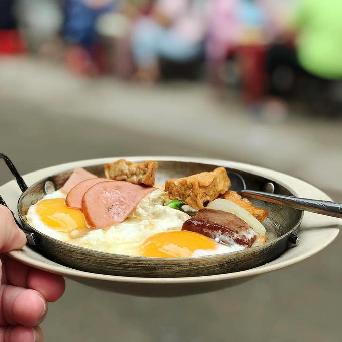 Bạn có thể gọi phần ốp la kèm thịt nguội riêng hay phần thập cẩm, rắc lên ít tiêu, nước tương, tương ớt là bạn có thể thưởng thức. Khách sẽ ngồi trên ghế nhựa trong một con hẻm nhỏ. Giá một phần bánh mì ăn trên chảo từ 40.000 đồng.