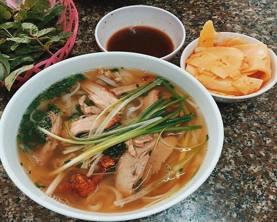 Phở vịt quay: Đây là món mang hương vị độc đáo của đặc sản xứ Lạng. Bát phở ở quán bao gồm đầy đủ sợi phở, hành, gia vị nhưng thay vì thịt bò hay gà, thực khách sẽ được thưởng thức những miếng thịt vịt quay chín mềm, đậm đà và thơm phức với lớp da đỏ bóng, mỡ màng. Ngoài phở, quán còn phục vụ vịt áp chảo, vịt nấu chao, cháo vịt quay, vịt luộc... Quán thường đông khách vào khung giờ 6h - 14h và 16h - 20h hàng ngày, giá một tô là 30.000 đồng. Ảnh: Bảo Trung.