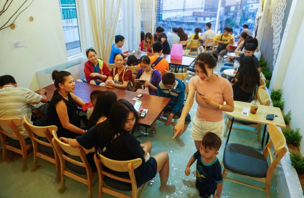 Amix Coffee  Nằm ngay mặt tiền đường Phạm Văn Hai, quận Tân Bình, quán cà phê được thiết kế có nhiều tầng. Vào quán, khách sẽ gọi món trước ở tầng trệt rồi thoải mái lựa chọn không gian ngồi ở hai tầng trên.  Điều khiến thực khách thích thú và tạo "cơn sốt" khi quán vừa mới hoạt động hồi tháng 6 là không gian bể cá cho khách lội vào bên trong. Mô hình do Ngô Được Hòa (22 tuổi) nghĩ ra. Theo đó, bể nước rộng 25 m2 và nuôi thả nhiều loại cá. Ảnh: Quỳnh Trần.