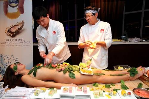 Đầu bếp trình bày đồ ăn lên cơ thể người mẫu trước môt bữa tiệc Nyotaimori. Ảnh: Blogspot