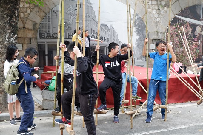 Trẻ em tham gia trò chơi dân gian đi cà kheo tại phố bích họa Phùng Hưng.