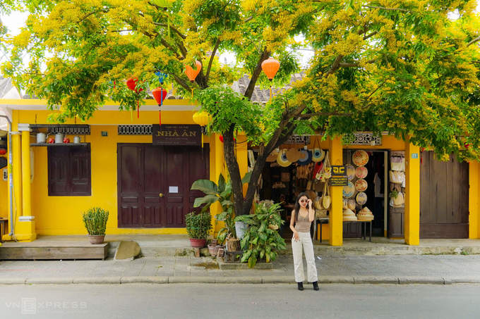 Nữ du khách chụp hình trước cửa hàng bán nón lá trên đường Phan Chu Trinh.