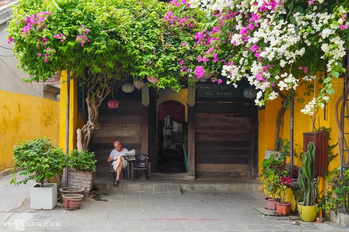Hội An yên vắng với cụ ông đọc báo trước hiên nhà phủ hoa giấy