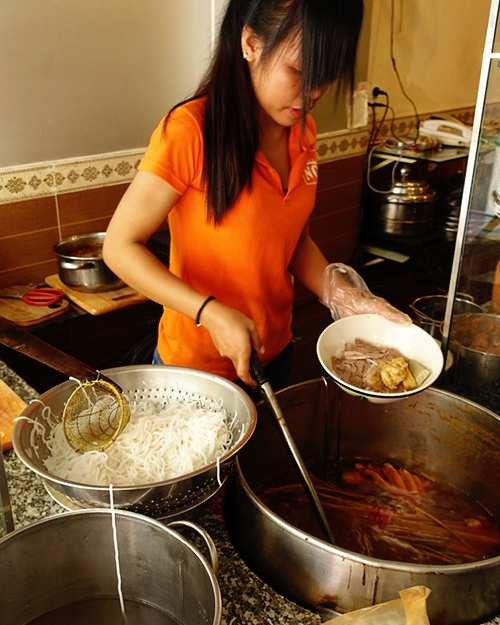 Quán ăn nằm trên đường Bùi Viện, quận 1. Theo chị Huỳnh Giao, chủ quán hiện tại, quán do ông bà của chị mở từ những năm 90 của thế kỷ trước, ban đầu chỉ bán trên gánh ở vỉa hè Sài Gòn. "Tất cả công thức đều được truyền từ ông bà đến cha mẹ và tôi", chị Giao cho hay. Các nguyên liệu như chả tôm, chả cua đều do quán tự làm. Trong hình là nhân viên bếp của quán. Ảnh: @auntierim_s.