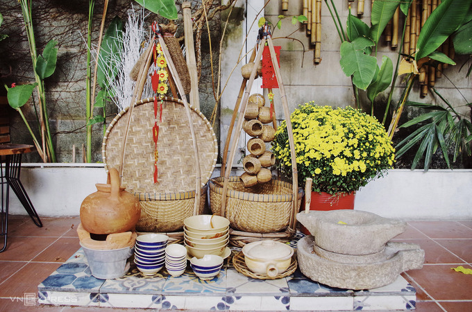 Bên cạnh các tiểu cảnh chủ đề Tết tại quán cà phê Hội An Mystery, quán còn trưng bày những hiện vật dân dã, phù hợp với phong cách quán. Chủ quán thiết kế một góc bếp trong khuôn viên, với chiếc cối đá là vật không thể thiếu để xay bột làm mì Quảng.