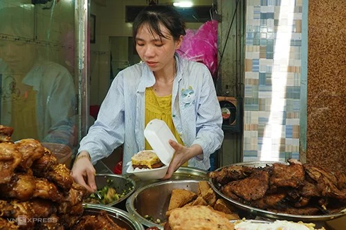 Chị Ngọc Châu, con gái chủ quán tất bật bán cơm tấm sà bì chưởng cho khách mua mang về. Ảnh: Di Vỹ.