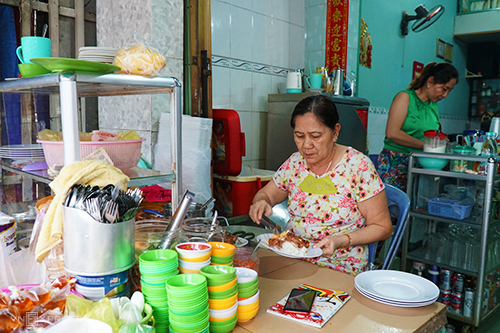 Bàn gỗ chuẩn bị món ăn tại quán cơm tấm Nguyên. Chị Hà và mẹ thay phiên ngồi quầy. Ảnh: Di Vỹ.