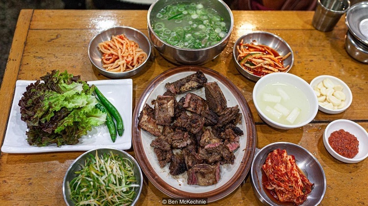 Thực khách ăn sườn bò nướng Seoul galbi có thể ăn kèm kimchi, rau diếp, ớt xanh và chấm sốt ớt. Ảnh: Ben Mckechnie.