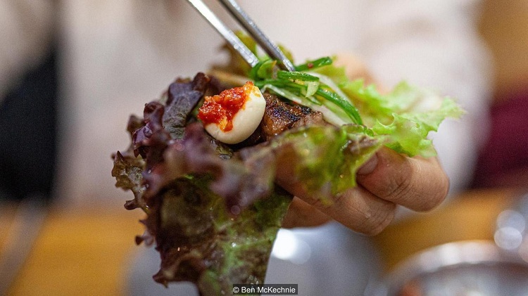 Bàn ăn sườn bò nướng Seoul tại Joseonok với bát đũa kim loại, kimchi và rau sống. Ảnh: Ben McKechnie.