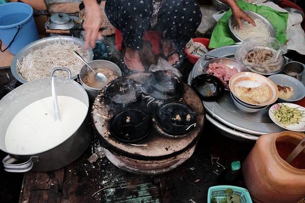 Cô chủ quán ngồi trên sạp cao hơn đổ từng mẻ bánh xèo nhỏ khoảng 10 cm với nguyên liệu gồm vỏ bánh, giá, thịt, tôm (7.000 đồng/cái).