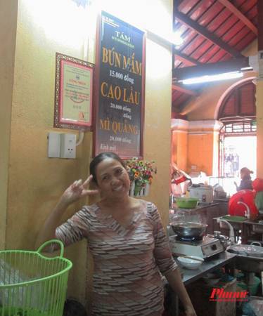 Cô có bán cả mì Quảng, bún mắm, “giá chuẩn” là từ 15 đến 20.000 đồng nhưng nếu bạn đang no, muốn ăn ít hơn thì cứ nói, cô sẽ bớt lại, bán đúng giá tiền mà khách muốn ăn. Tô cao lầu mà tôi “đặt hàng” có giá 15.000 đồng (thay vì 20.000 đồng), vẫn nhiều thịt, có bột chiên giòn giòn, rau xanh tươi rói rất đậm đà. Sau khi vui vẻ bán cho khách, cô chủ còn “xì tin” tạo dáng thế này.