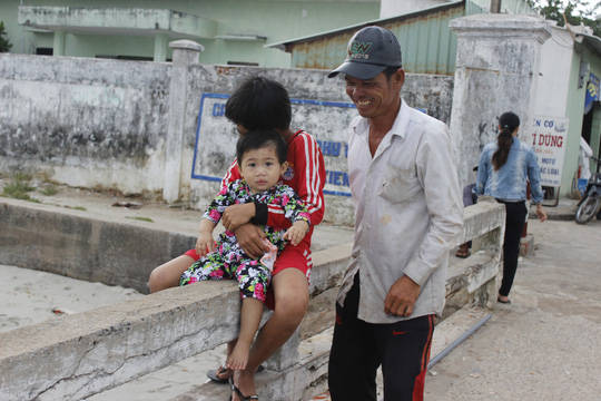 Hai anh em ở Thổ Chu đang ngồi ngoài cảng để chờ ba mẹ đánh cá trở về