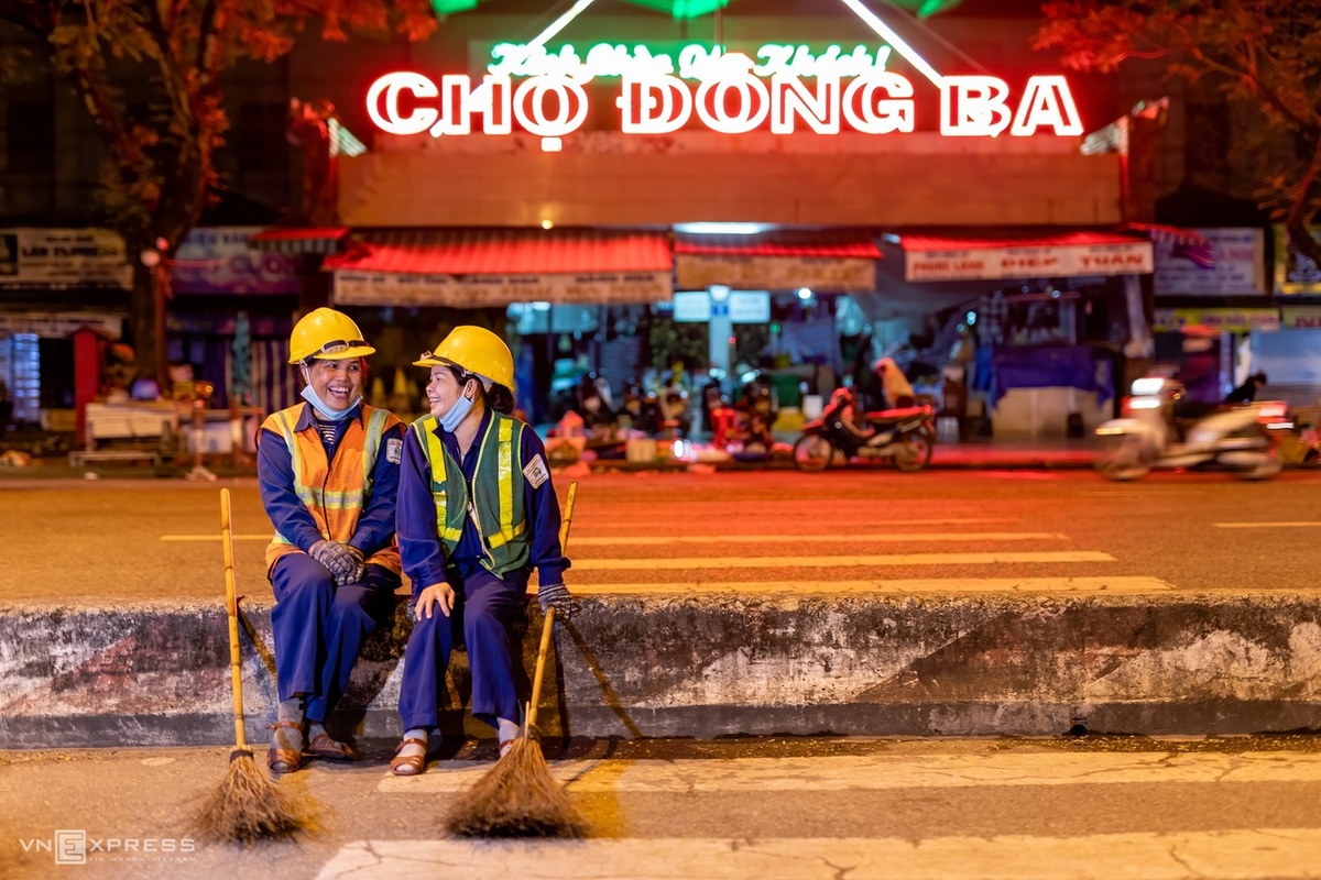 Hai nữ công nhân công trình đô thị nghỉ giải lao trước chợ Đông Ba.  Chợ này nằm trên đường Trần Hưng Đạo, TP Huế, là chợ lớn nhất tỉnh, ra đời dưới thời vua Đồng Khánh (năm 1887). Xưa chợ nằm gần cửa Đông Ba, sau đó vua Thành Thái cho di dời về vị trí như hiện nay.