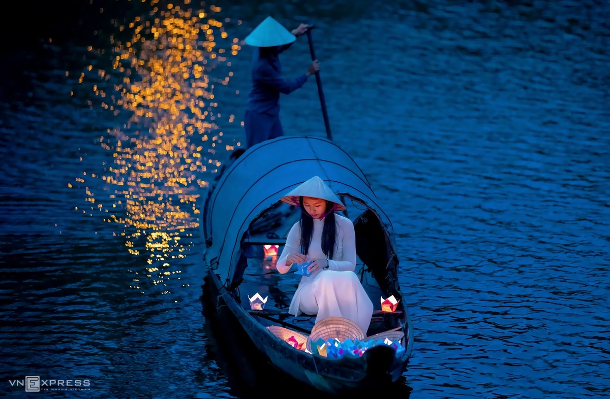 Thiếu nữ diện áo dài trắng trong hoạt cảnh thả Hoa đăng trên dòng Như Ý vào dịp Festival Huế. Những ước muốn của người già, người trẻ đều được gửi vào những cánh hoa đăng trôi nhẹ trên dòng sông, cầu mong no ấm, an lạc và luôn được hạnh phúc.